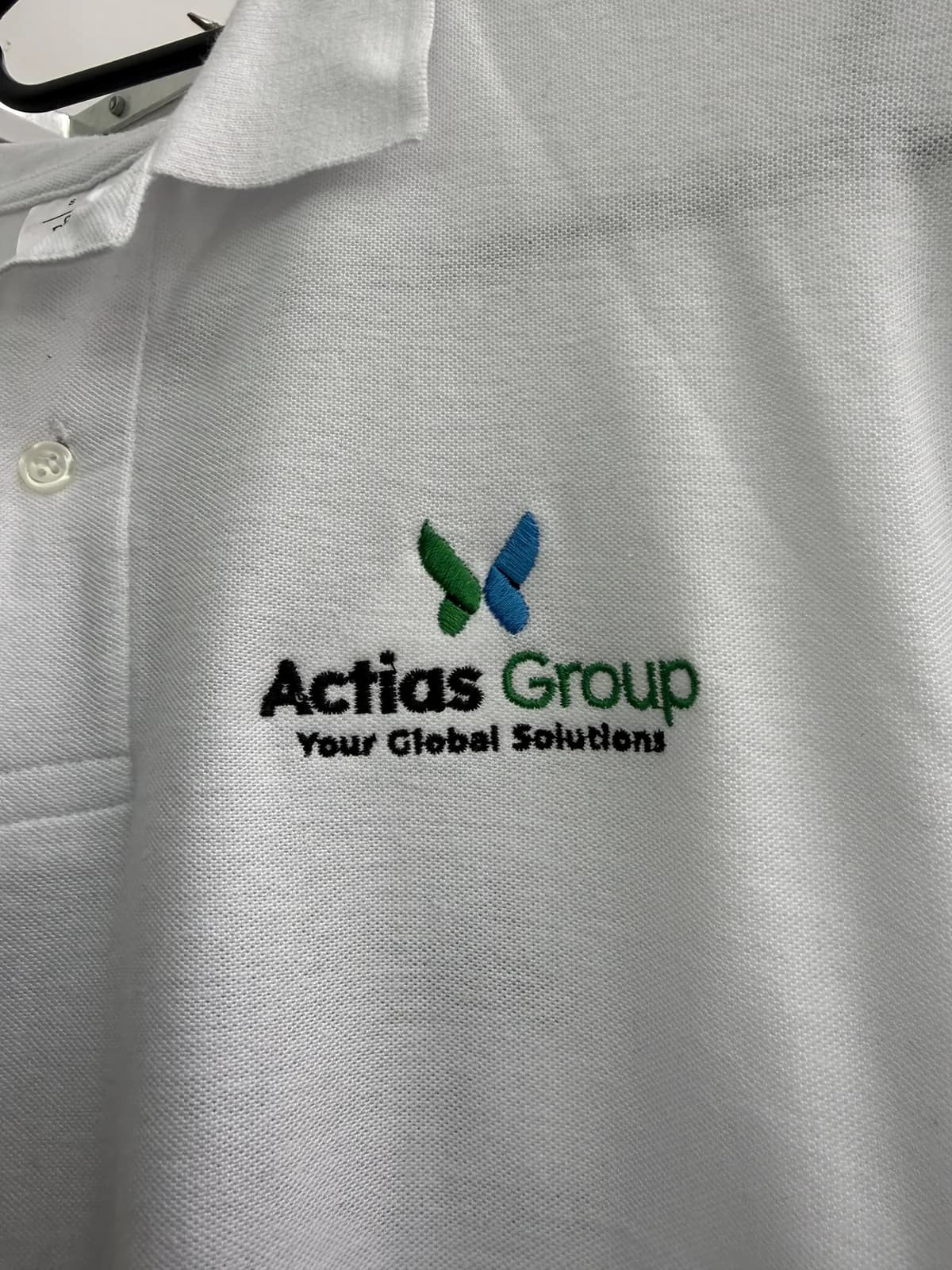 Polo blanc brodé au logo Actias Group sur la poitrine, personnalisation textile par AB2 Print