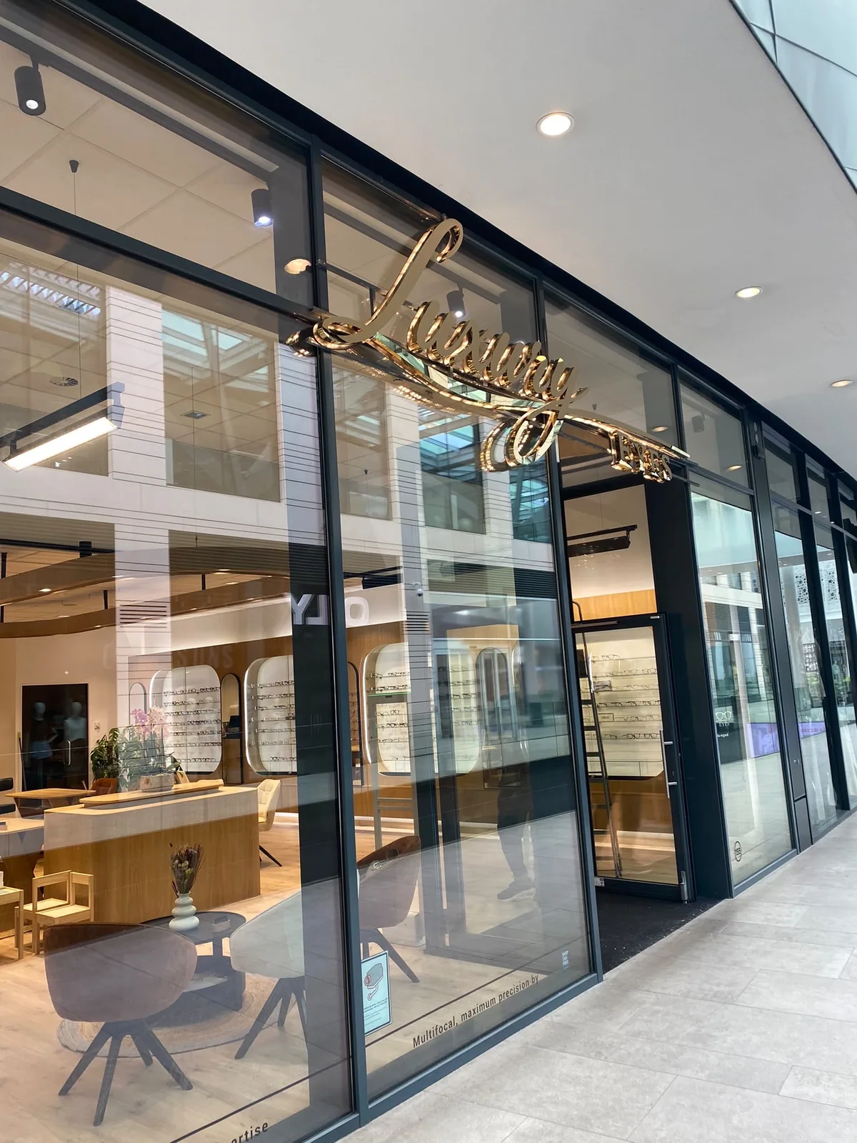 Enseigne en lettres scriptes dorées « Luxury » posée sur la vitrine d'une boutique d'optique