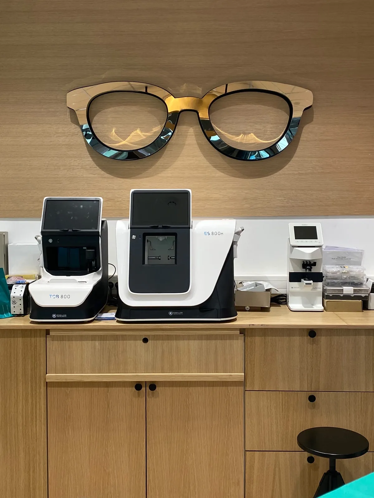 Décoration sur mesure en forme de lunettes géantes découpées, posée au-dessus du comptoir d'une boutique d'optique
